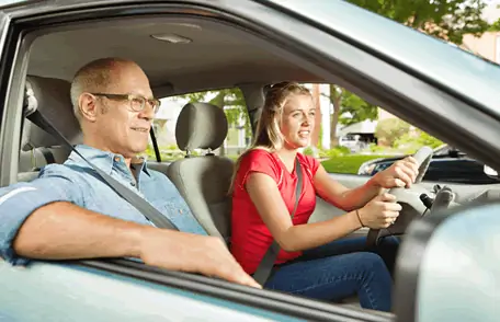 Image of a teen driving with her father