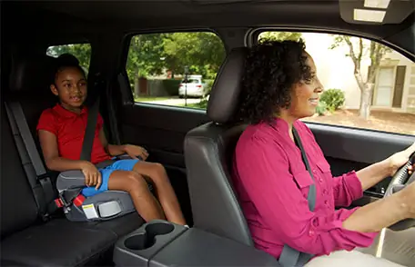 Mother driving car with daughter in booster seat