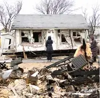 A person standing in front of a home destroyed by a hurricane