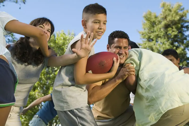 young boy playing football with family members young boy playing football with family members