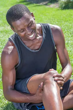 Мужчина держит колено