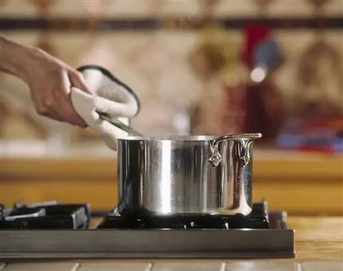 Женщина ставит кастрюлю на плиту