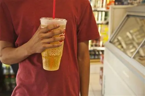 Молодой человек пьет большую газировку