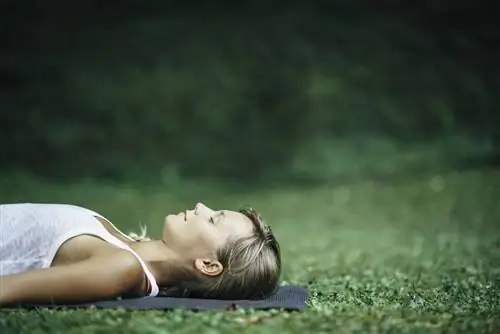 женщина отдыхает на коврике для йоги