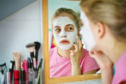 Девушка надевает маску для лица в ванной