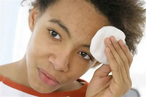 молодой человек использует очищающую подушечку для очистки лица