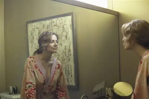 Женщина смотрит в зеркало в халате