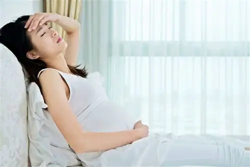 Беременная женщина сидит в постели