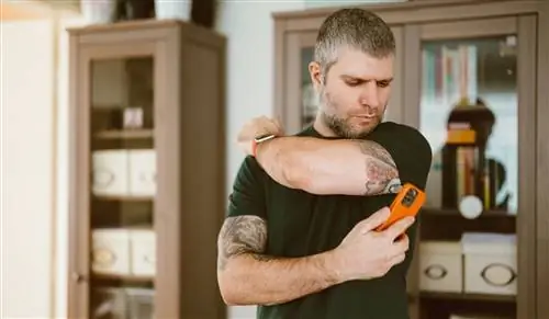 Татуированный мужчина с диабетом проверяет уровень сахара в крови