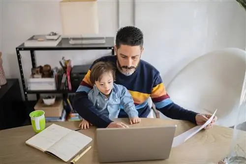 Родитель работает дома на ноутбуке с ребенком с особыми потребностями