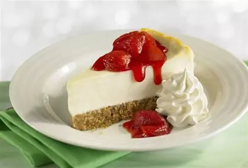 Кусочек чизкейка с клубникой и взбитыми сливками.