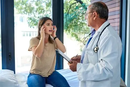 Женщина с головной болью разговаривает с врачом о менингите