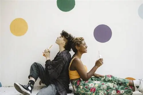 Два подростка сидят спиной к спине.