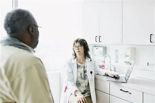 Улыбающаяся женщина-врач консультируется со старшим пациентом-мужчиной в смотровой комнате