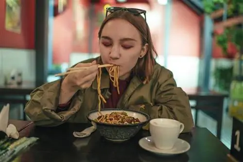 Человек ест палочками в ресторане