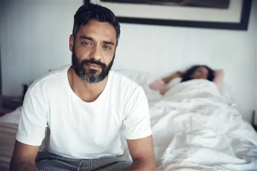 мужчина сидит на краю кровати