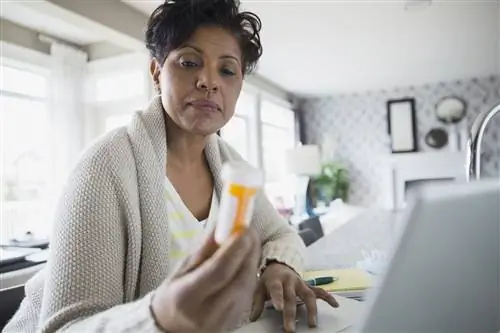 Пожилые чернокожие женщины смотрят на бутылку с лекарством, отпускаемым по рецепту.