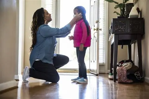 Мать надевает маску на своего ребенка.