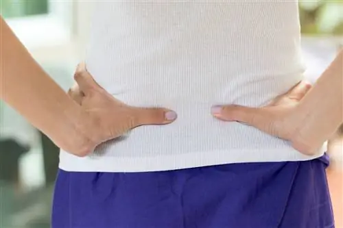 женщина с болью в спине держится за спину