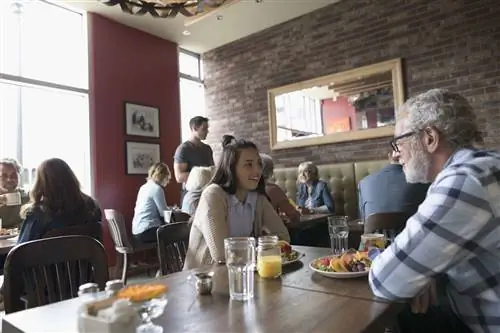 Дедушка и внучка-подросток разговаривают, обедают за обеденным столом