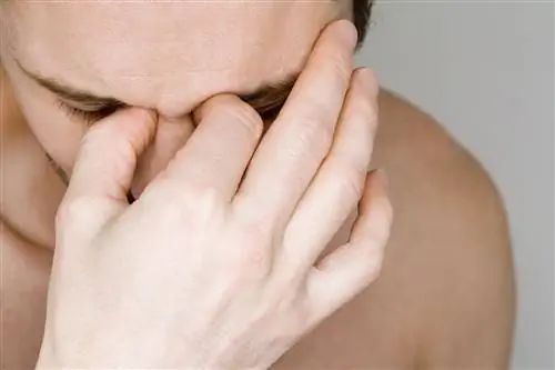 Мужчина держит переносицу от боли