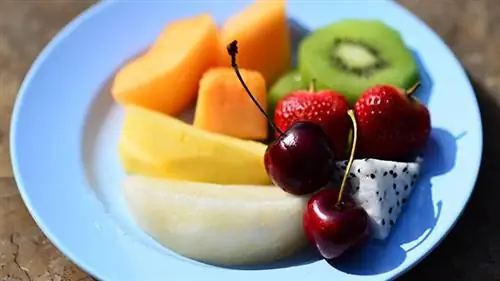 синяя тарелка с нарезанными фруктами сверху, мускусная дыня, манго, груша, киви, клубника, вишня, драконий фрукт