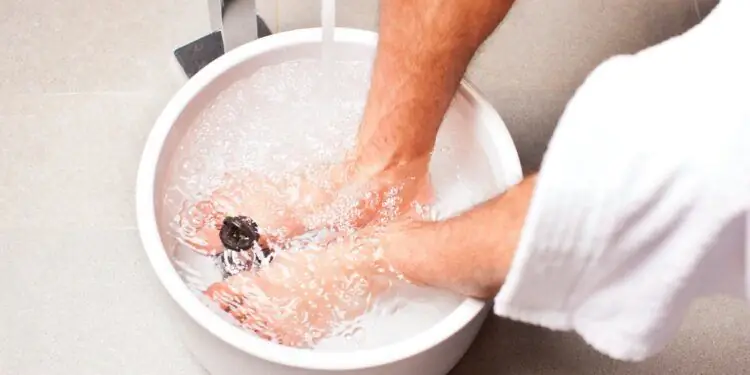 Ноги и икры мужчины в миске с водой Ноги и икры мужчины в миске с водой