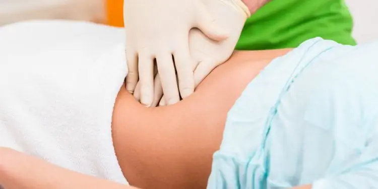 Терапевт массирует живот женщины