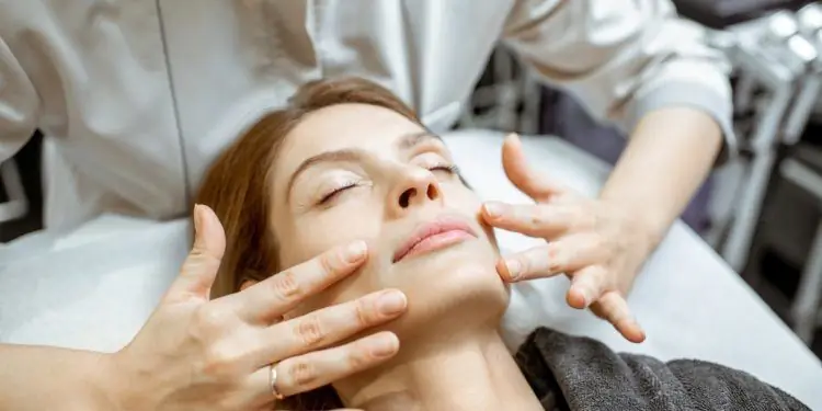 Терапевт выполняет лимфодренаж на лице женщины