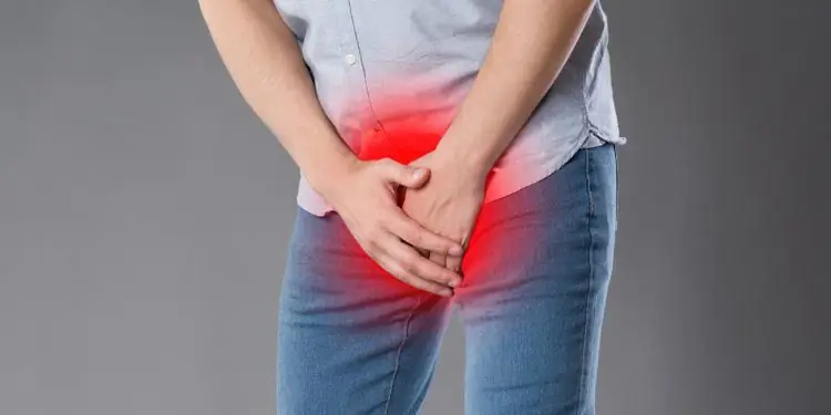 Мужчина держит руки перед болезненной областью гениталий